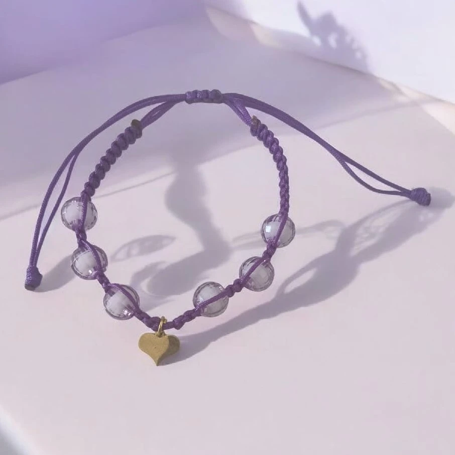MANILLA COSIDA MORADA CON DIJE DE CORAZÓN 
