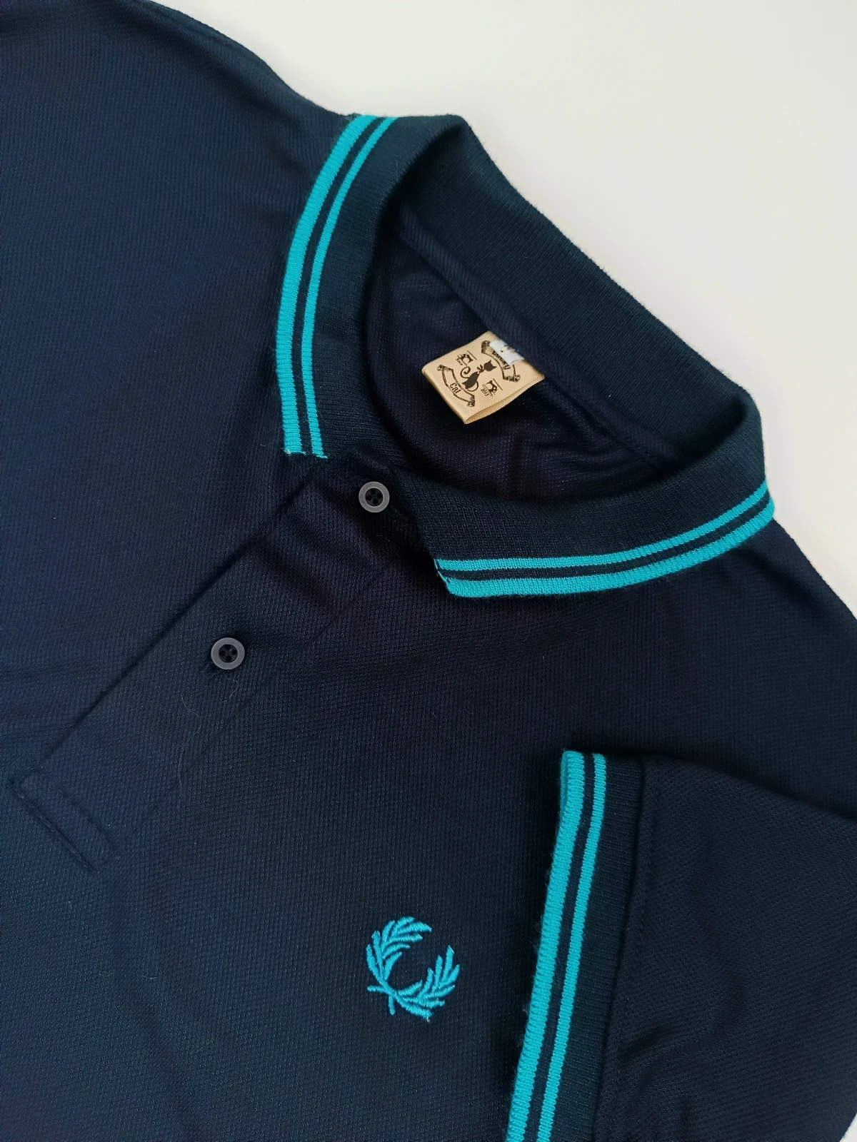 Camisa polo azul oscura con agua marina 