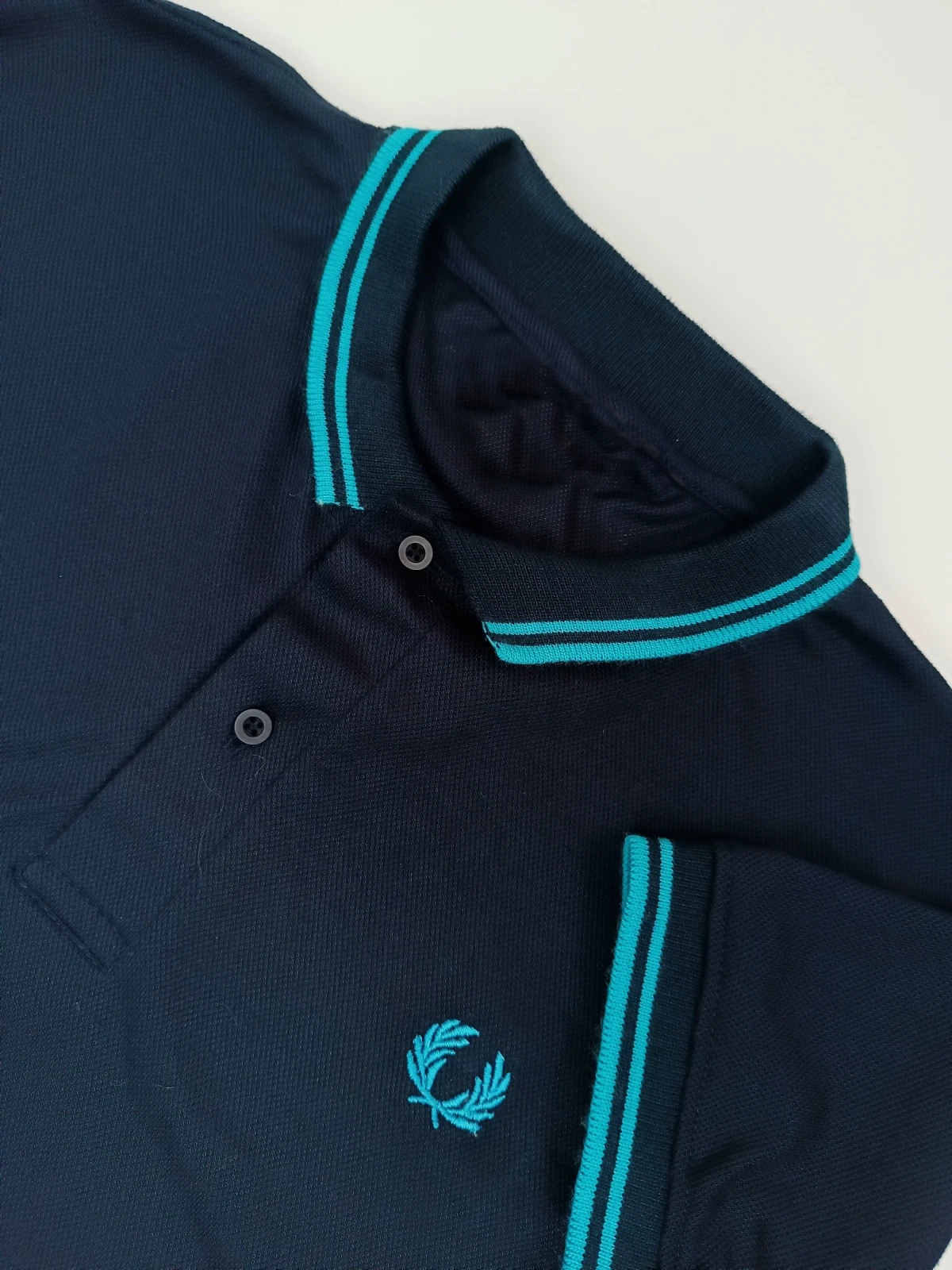 Camisa polo azul oscuro con agua marina