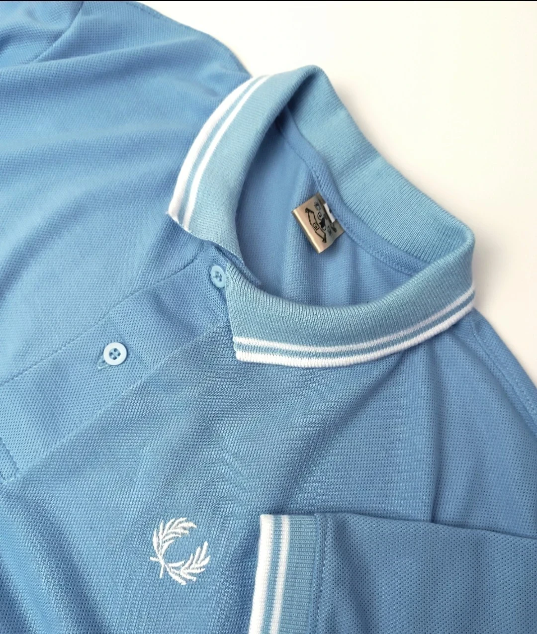 Camisa Polo azul claro con líneas blancas