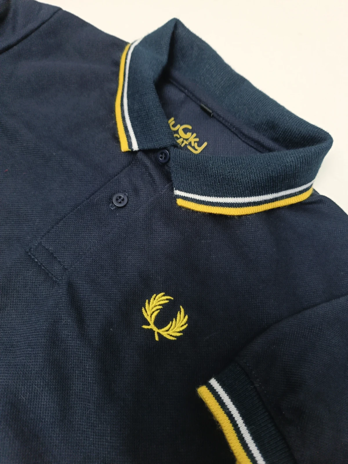 Camisa polo azul oscuro con linea amarilla y blanca 