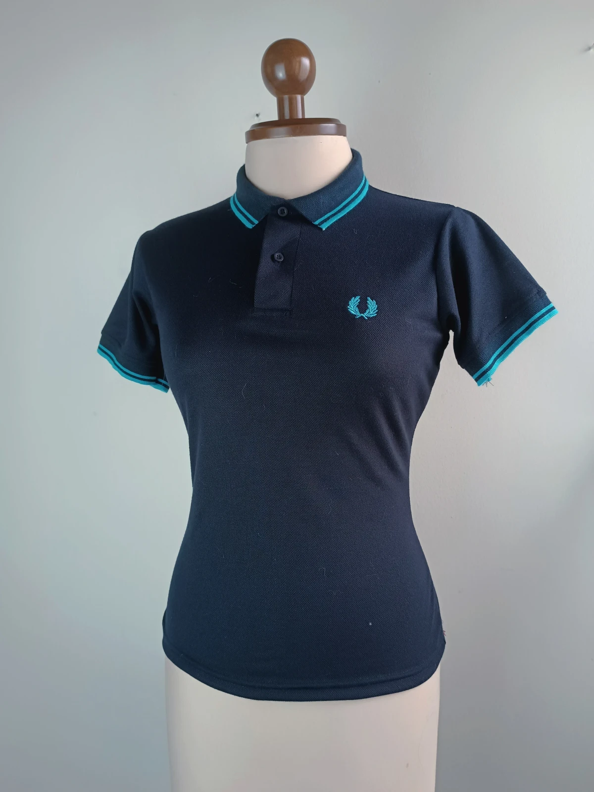 Camisa polo azul oscura con líneas agua marina